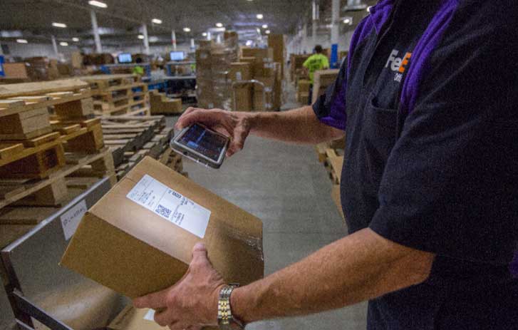 Một nhân viên FedEx đang quét một chiếc hộp Pekerja FedEx sedang memindai kotak